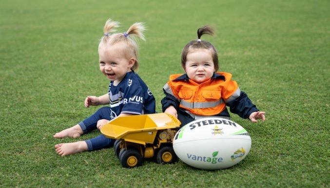 The stars of the campaign: Bijou Wilson (left, in the arms of Cowboys Five-Eighth Tom Dearden) and Estelle Sadlier (right, held by mum Dyhan Sadlier) along with Cowboys Hooker, Jake Granville.