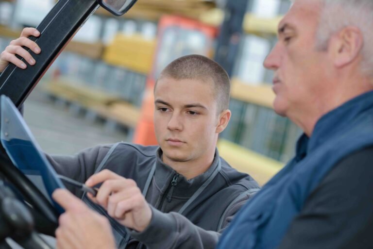 Instructor teaching apprentice about heavy vehicles.
