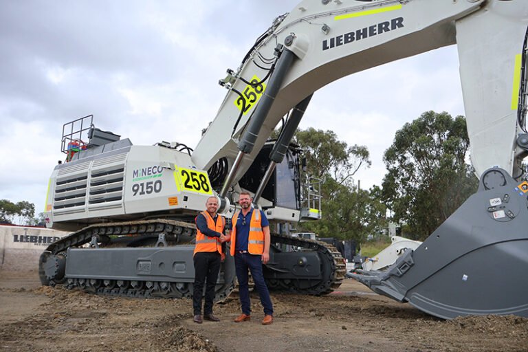 (Image source: Liebherr-Australia) Daniel Simone of Liebherr-Australia and Steven Arthur of Mineco with the first Liebherr machine to join Mineco’s fleet at Mount Arthur coal mine.